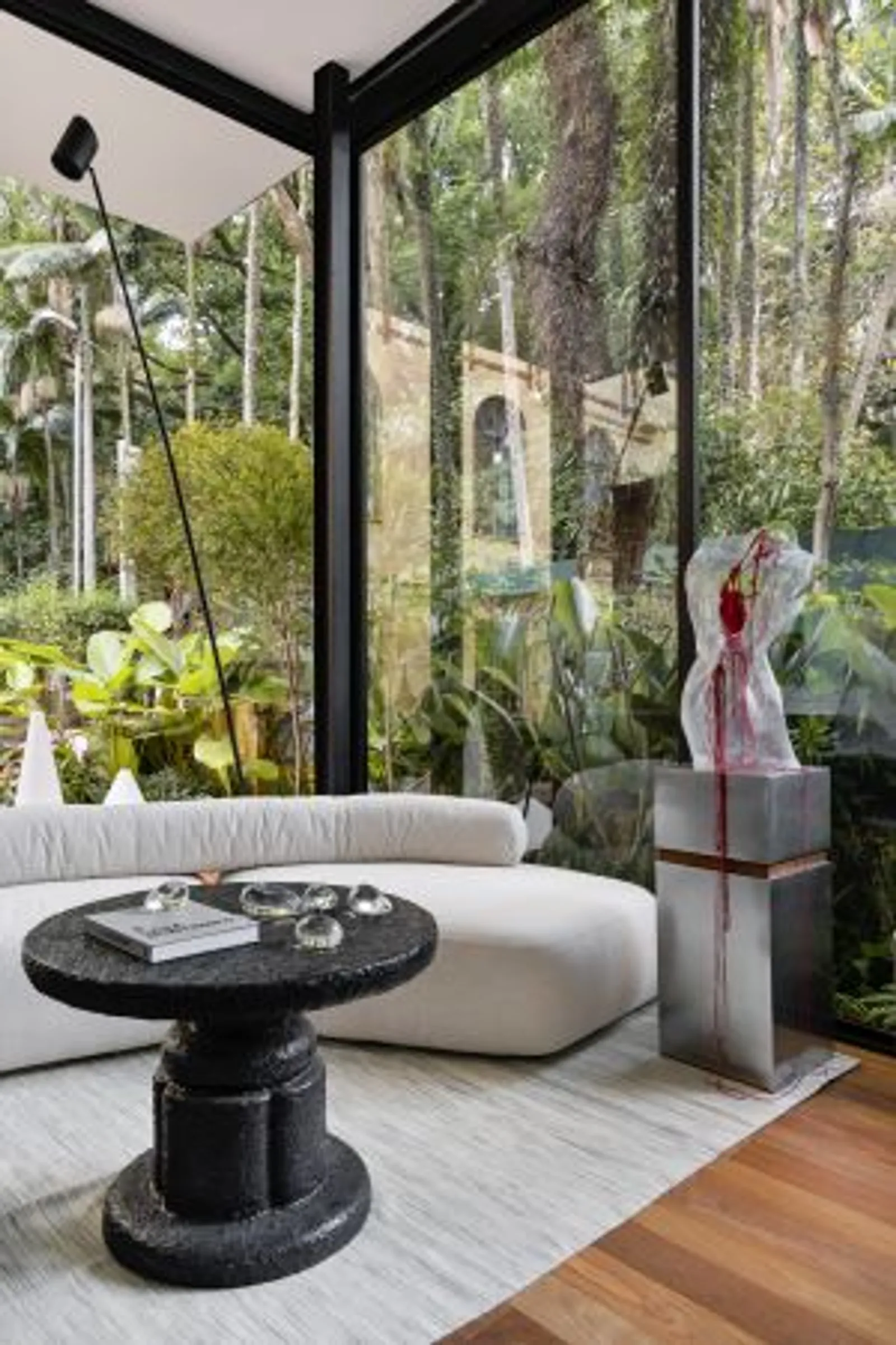 Ambiente interno da Casa Limiar R com grandes panos de vidro que integram o paisagismo de Bia Abreu e a natureza do Parque da Água Branca.