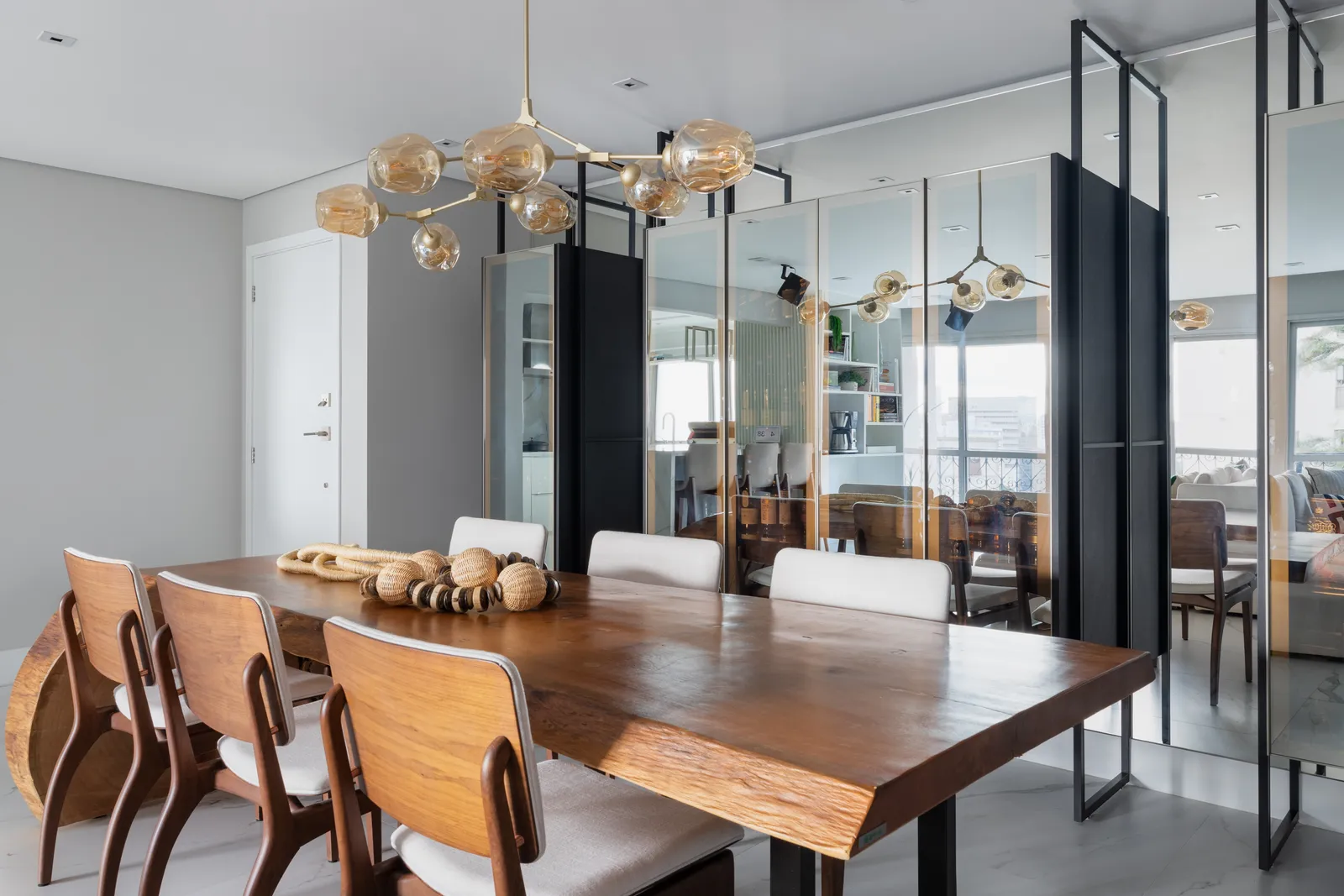 Na marcenaria que a arquiteta Daniela Funari realizou para esta sala de jantar, o vidro reflecta foi escolhido para as portas do móvel que guarda a coleção de whiskies dos proprietários. Contemporânea, a peça é estruturada com a serralheria que compreende a altura do piso ao teto | FOTOS: Julia Novoa