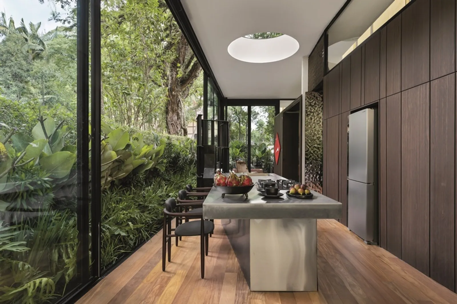 Cozinha do ambiente Casa Limiar R, com ilha e revestimentos em aço inox combinados com madeira natural.