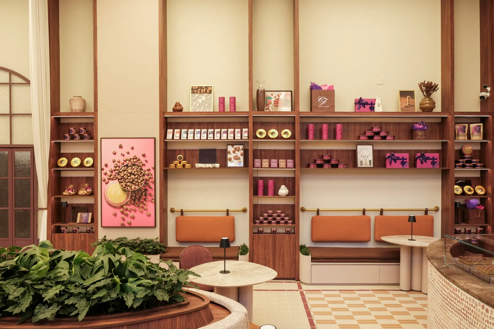 Projeto: Sitta + Barbo | Além das telas tensionadas, as arquitetas Amanda Sitta e Bruna Barbo também direcionaram a iluminação como recurso afetivo no ambiente ‘Tempo de Estar’. A luz aparece de forma pontual nas prateleiras do espaço dividido entre a Chocolat Du Jour e a Livraria UniSaber, a fim de valorizar os produtos das marcas