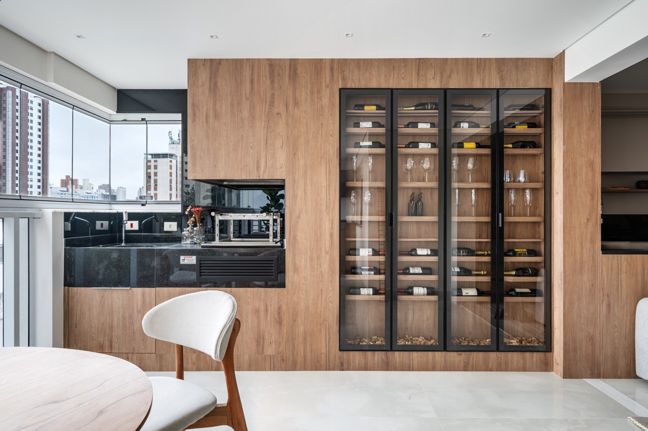 Projeto: Lima Vari Arquitetos | Detalhe da cozinha integrada com bancada e armários em tons claros, e adega embutida.