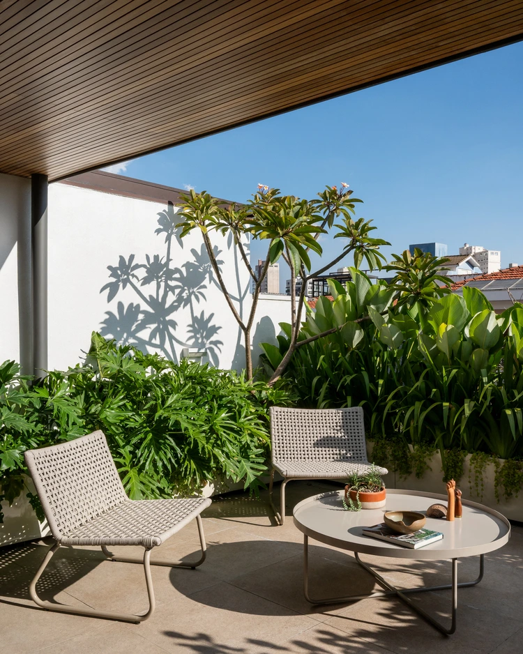 Projeto: MDH.Arq — Fernando Milan - Área de estar externa com sofás e poltronas, cercada por vegetação tropical, sob a p
