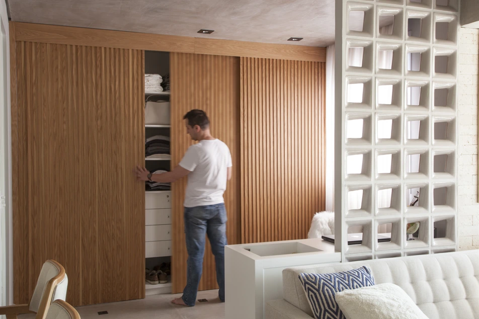 Projeto do BMA Studio | O painel de madeira esconde um guarda-roupas com portas de correr. Como este apartamento reformado pelo arquiteto Bruno Moraes tem apenas 50 m², essa foi a solução encontrada para ganhar espaço e abrigar roupas e objetos.