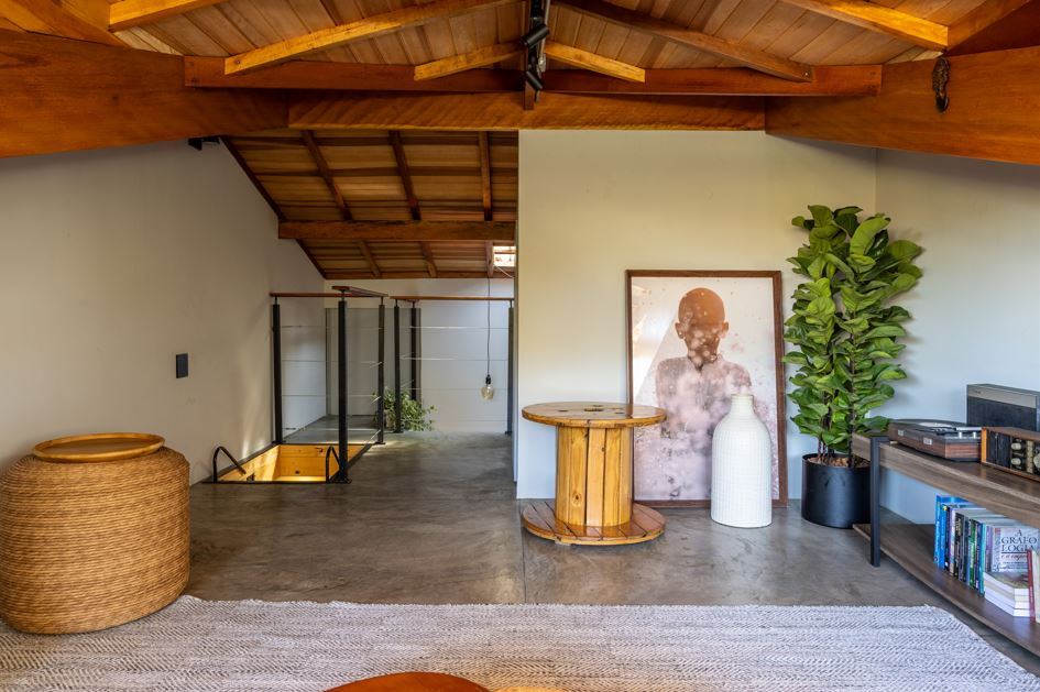 Projeto: Paulo Tripoloni | No sótão, planejado pelo arquiteto Paulo Tripoloni, a madeira estrutura o espaço e cria unidade, enquanto os volumes baixos, as fibras naturais e as peças de apoio arredondadas suavizam a composição.