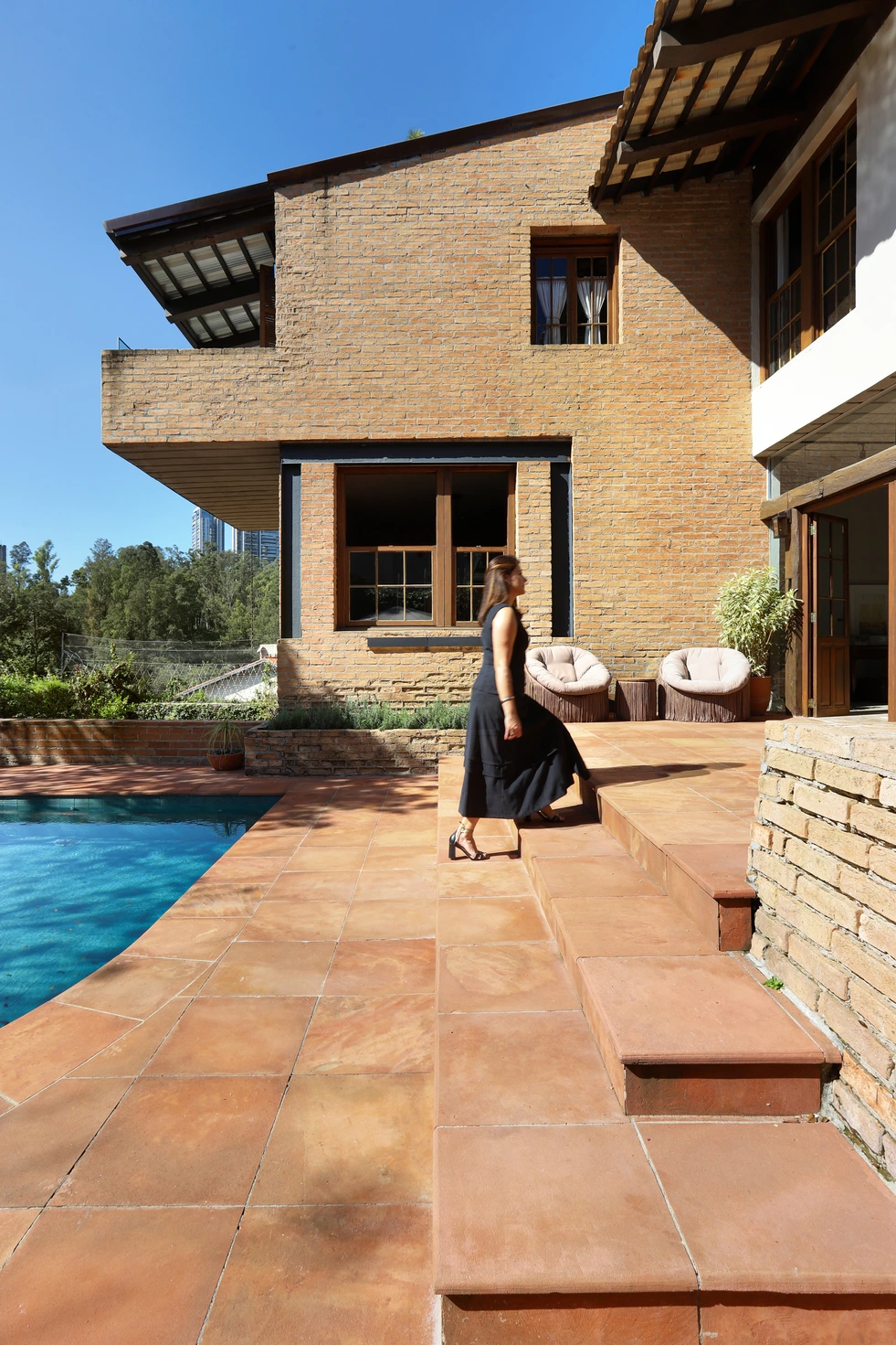 Vista da área externa com piscina e espreguiçadeiras, destacando a integração com a natureza.