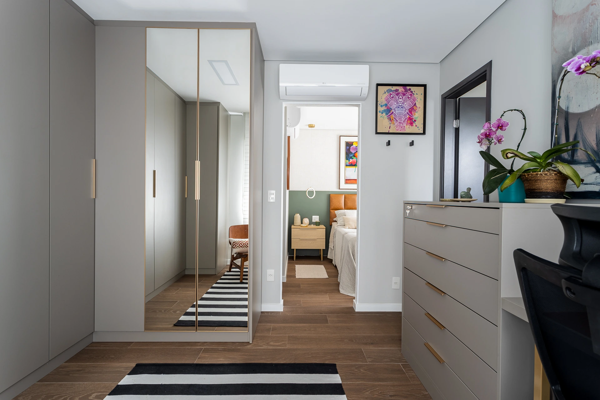 Projeto Camila Palladino | Closet amplo integrado ao quarto e banheiro, funcionando como área de transição com armários, cômodas e nichos.