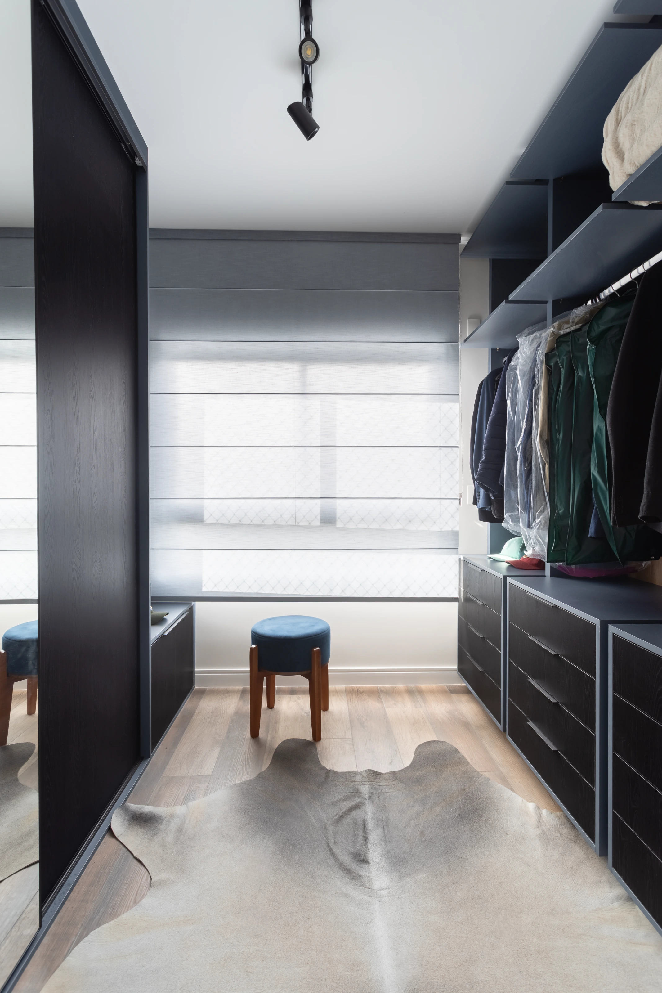 Projeto Camila Palladino | Vista detalhada de um closet com marcenaria planejada, incluindo prateleiras e gavetas para organização de roupas e acessórios.