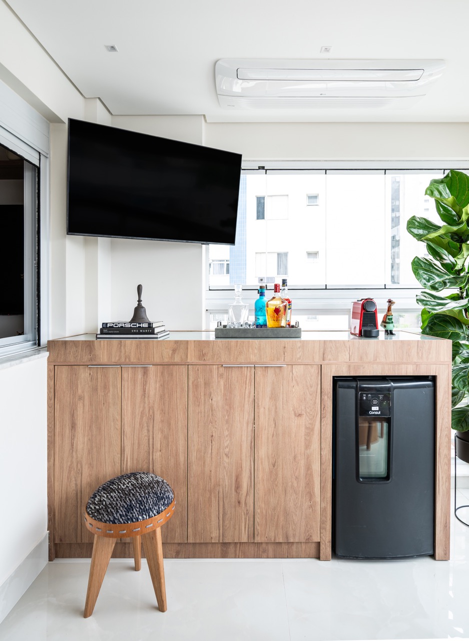 Projeto: Lima Vari Arquitetos | Vista da sala de estar integrada com a cozinha e a varanda, mostrando a paleta neutra e a iluminação planejada.